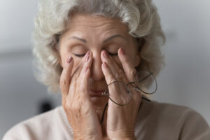 Close up of an older woman rubbing her eyes in fatigue, in need of hormone replacement therapy