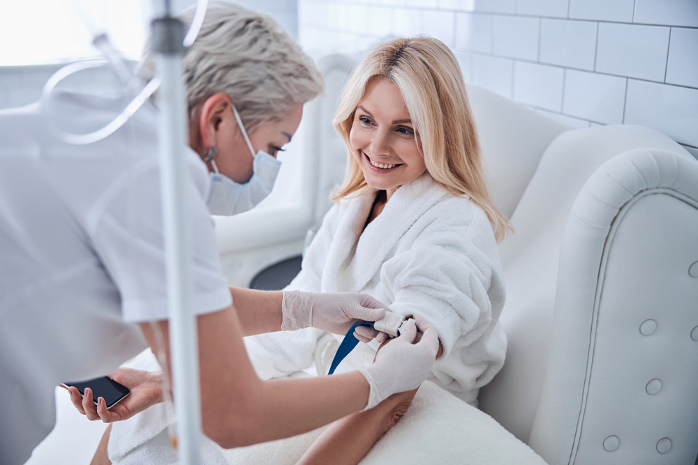 Older woman happily receiving her IV therapy treatment to feel refreshed and recharged.