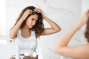 Frustrated young woman looking at her balding scalp, in need of PRP hair restoration