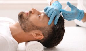 Close up of a man laying back and receiving PRP injections to his hair line to improve hair loss.